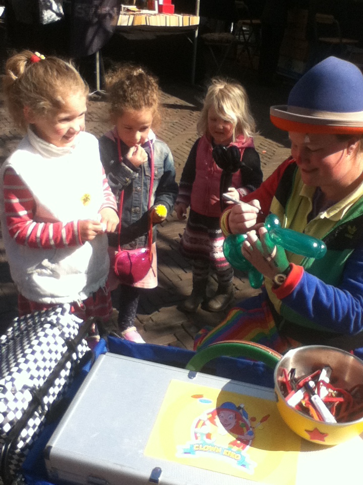 Clown Kiko is aan het ballonfiguren vouwen op de boekenmarkt in Wageningen