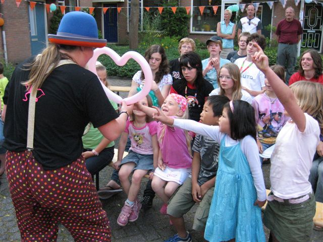 Ballonnenclown Kiko vouwt vrolijke ballonfiguren op een buurtfeest.